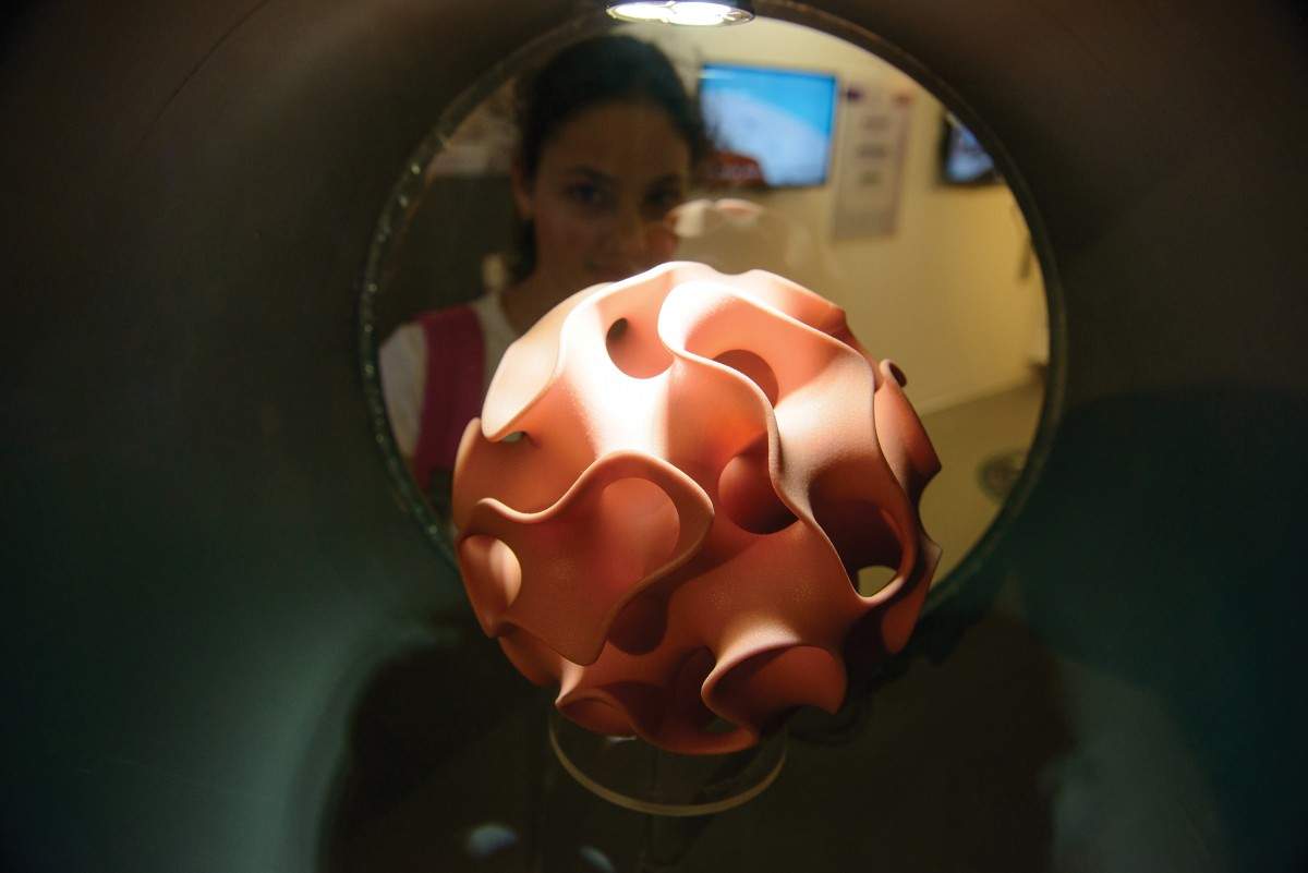 בתמונה: מבקרת בתערוכת "אימג'ינרי" המוצגת בגן המדע על-שם קלור, מתבוננת בדגם של גוף הקרוי גירואיד